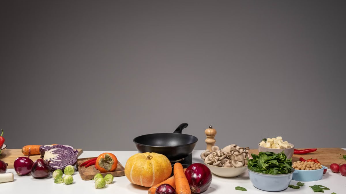 Studio composition of fresh vegetables and a frying pan, ideal for healthy cooking and recipe preparation.